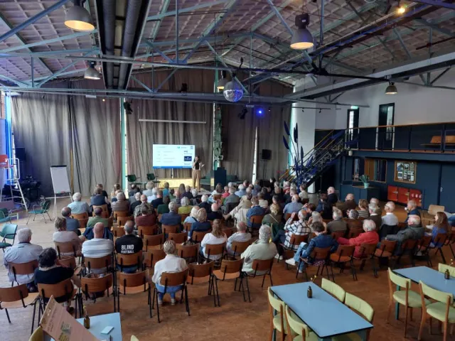 Patiëntenavond: afbeelding van een grote groep patiënten die kijken naar een presentatie van promovenda Woudstra
