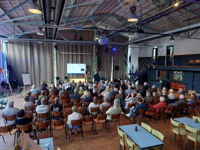 Patiëntenavond: afbeelding van een grote groep patiënten die kijken naar een presentatie van promovenda Woudstra
